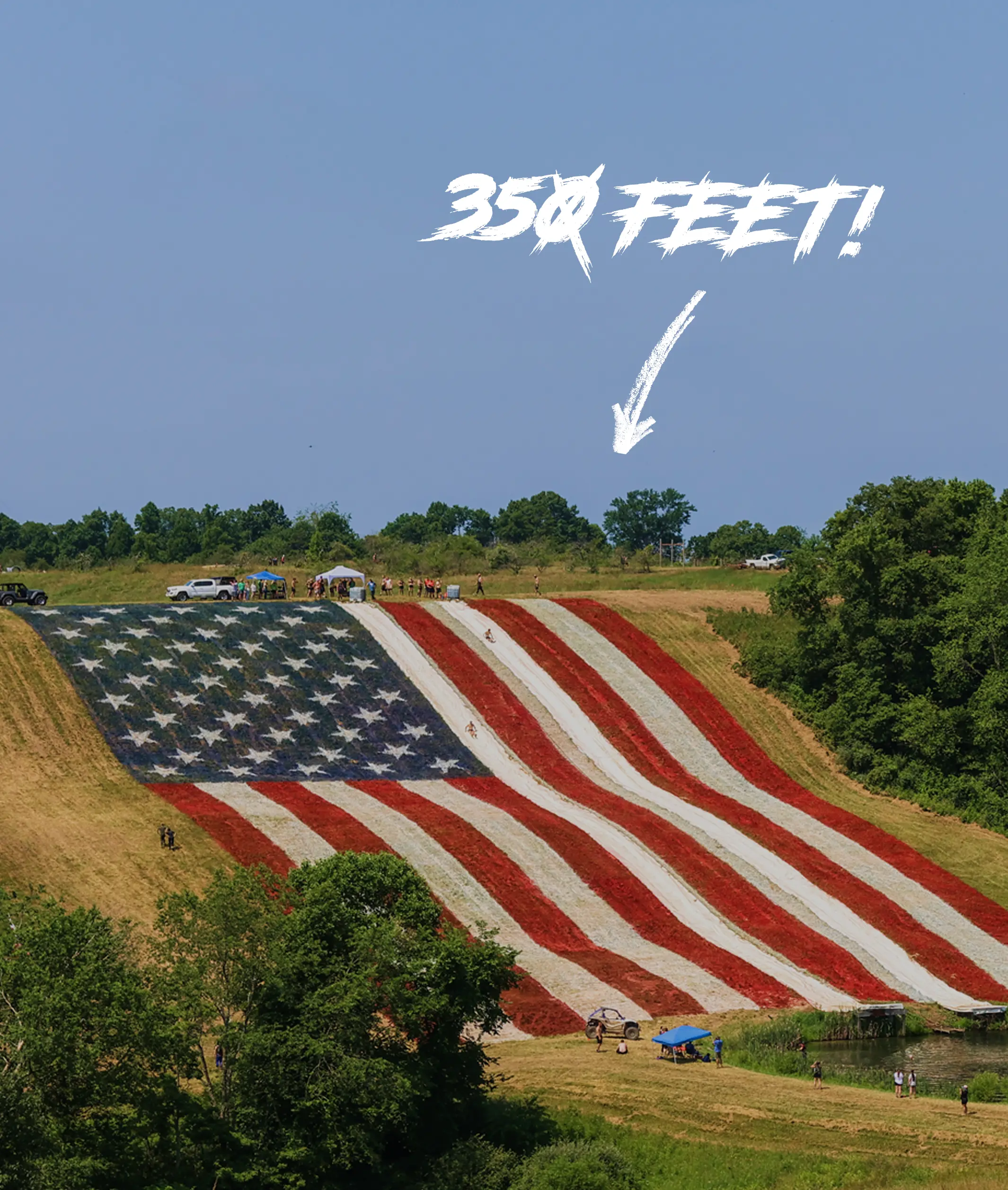 Large hill painted with an American flag design featuring red and white stripes and white stars on a blue field with people at the top and base, and text '350 FEET!' with an arrow pointing at the slide.